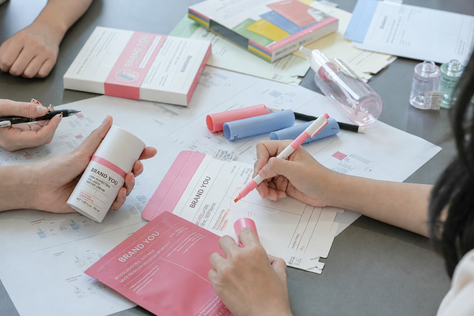 BrandYou team reviewing pink private-label product packaging and artwork